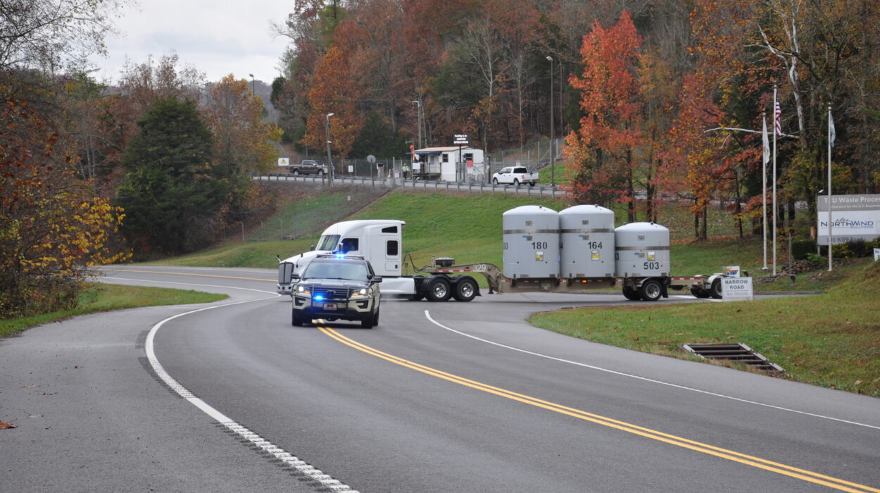 Photo of vehicle leading a semi-truck out with waste on the back