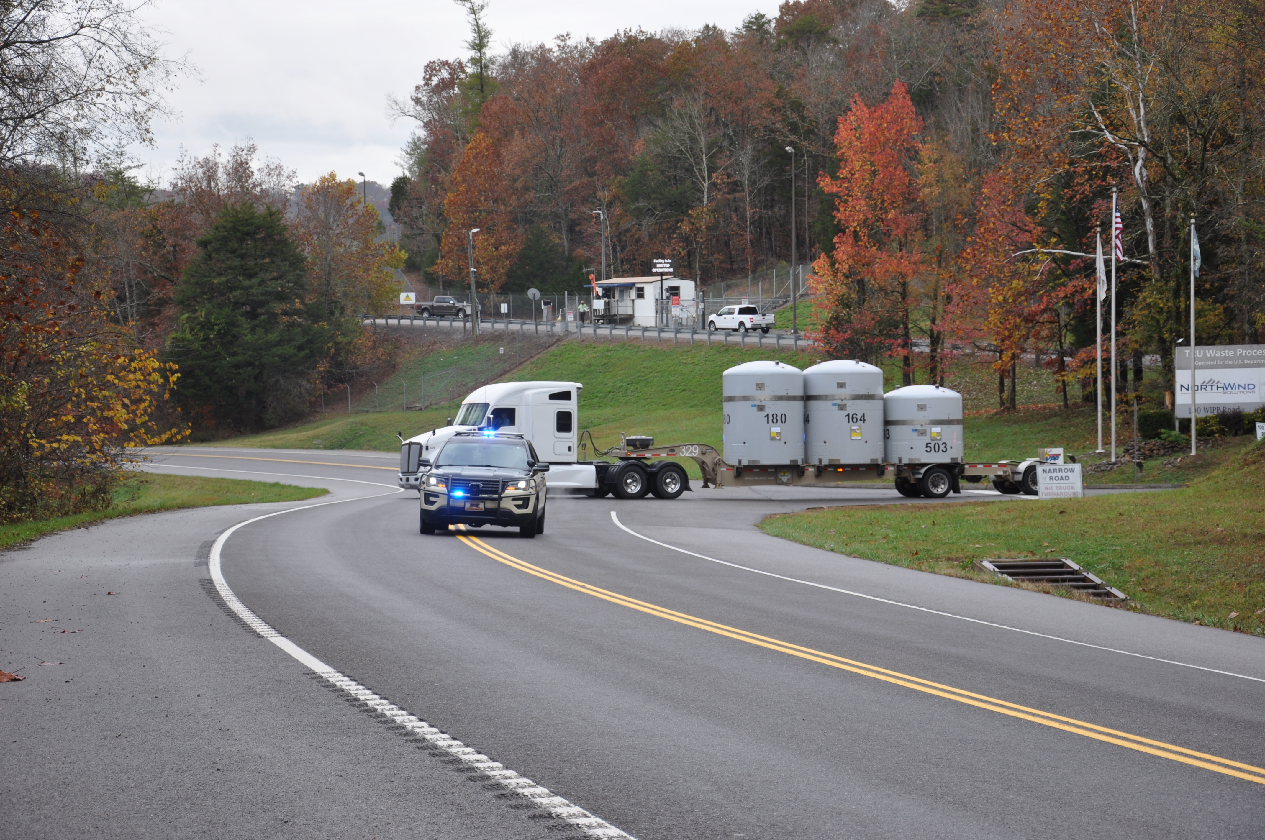 Photo of vehicle leading a semi-truck out with waste on the back