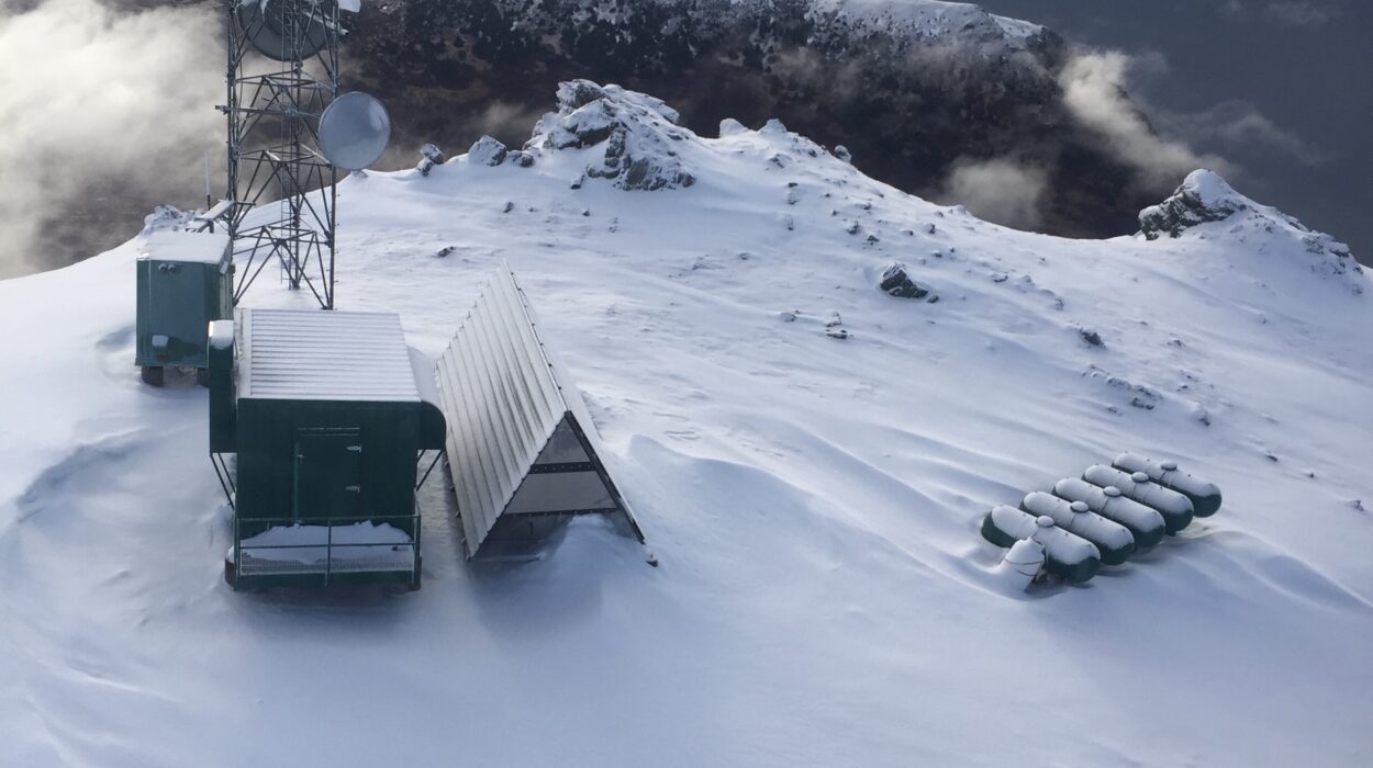 Aerial photo of snow-covered mountain with remote work site featuring a tower, 5 LP tanks, and two small buildings