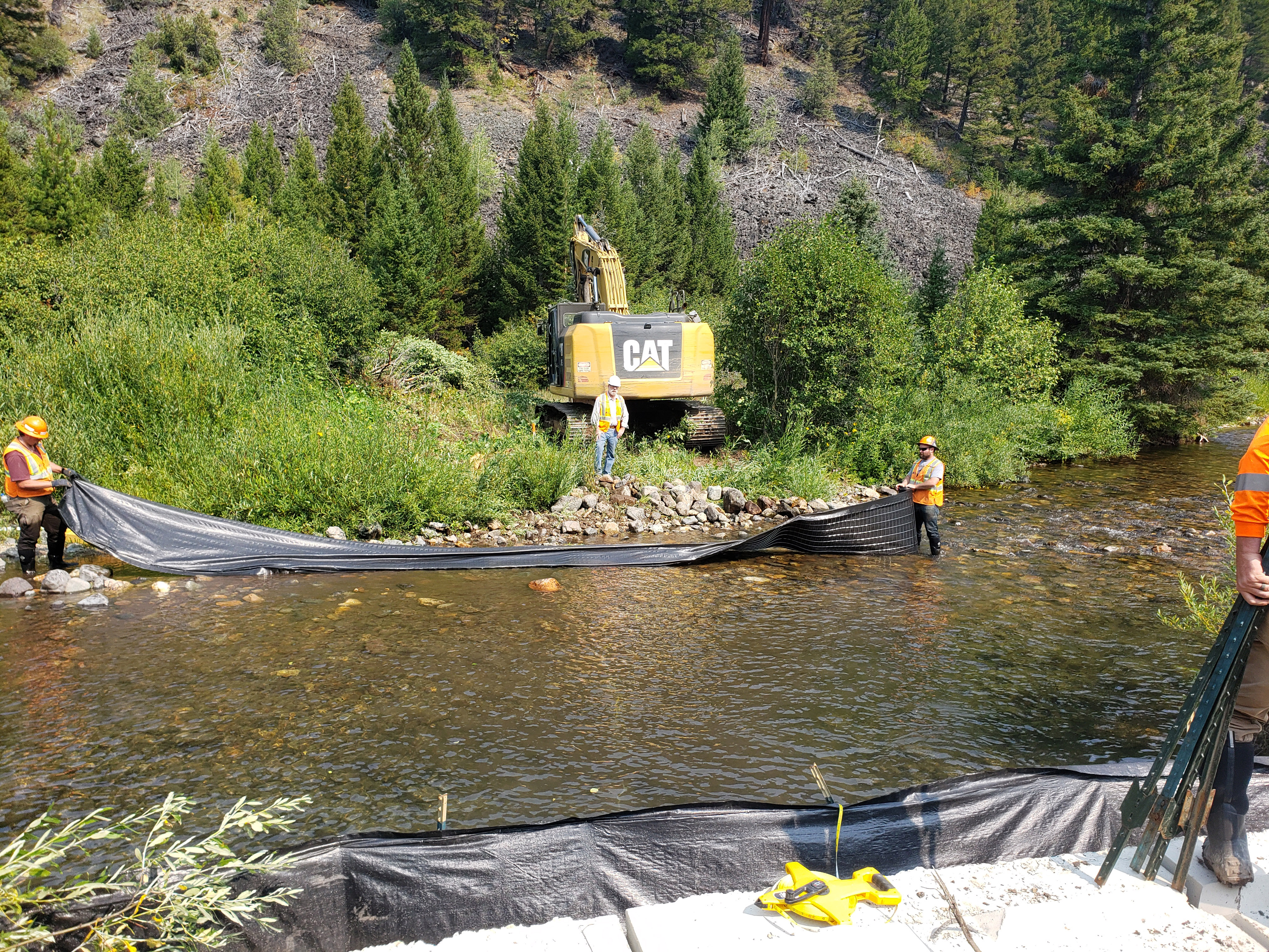 Photo of workers in small river at Tramway Creek Mining site setting the bank barriers