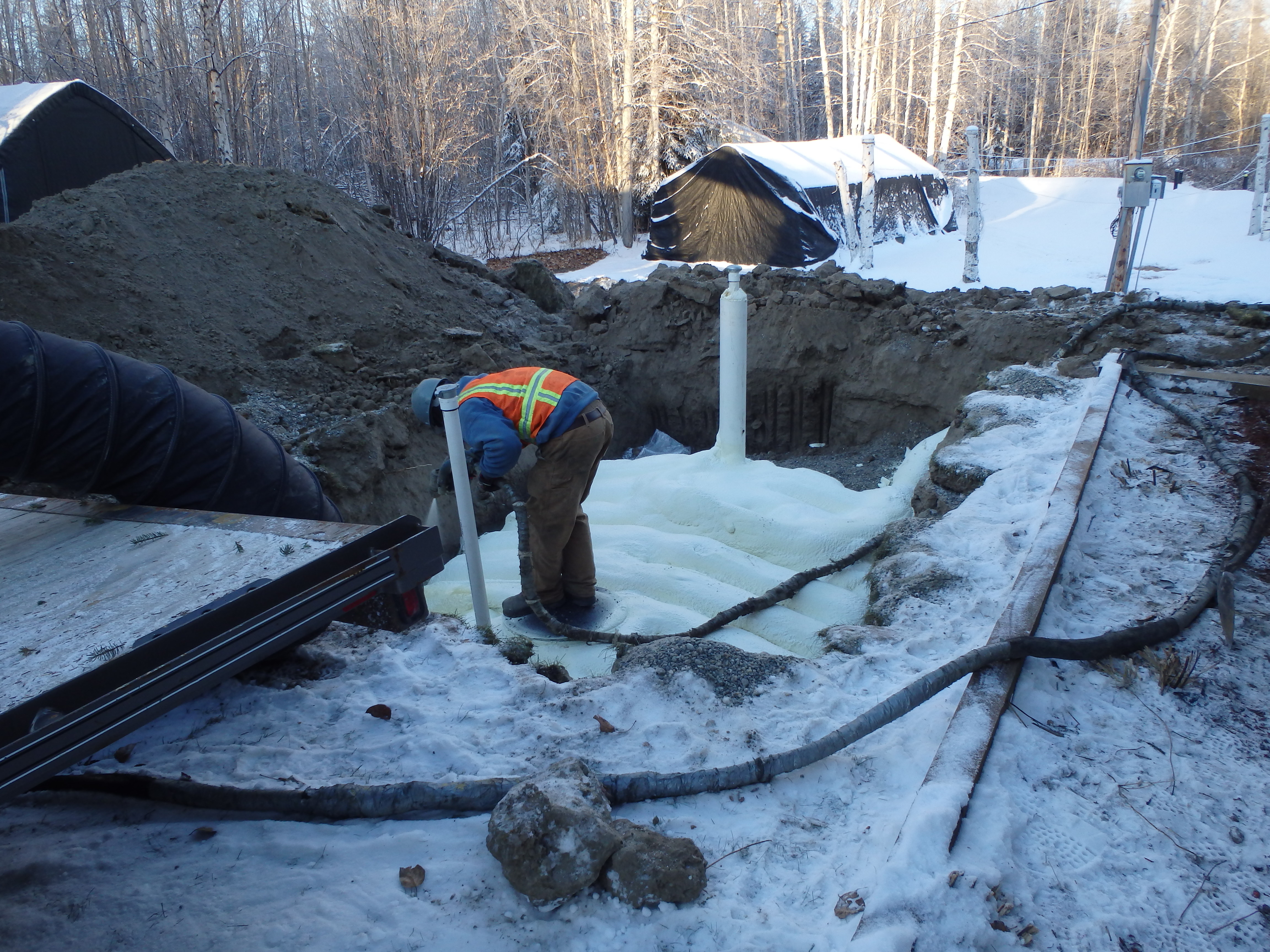 Photo of man working on-site with underground water tank and snow in Moose Creek, AK